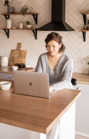 Woman Sitting Behind a Kitchen Counter and Using a Laptop